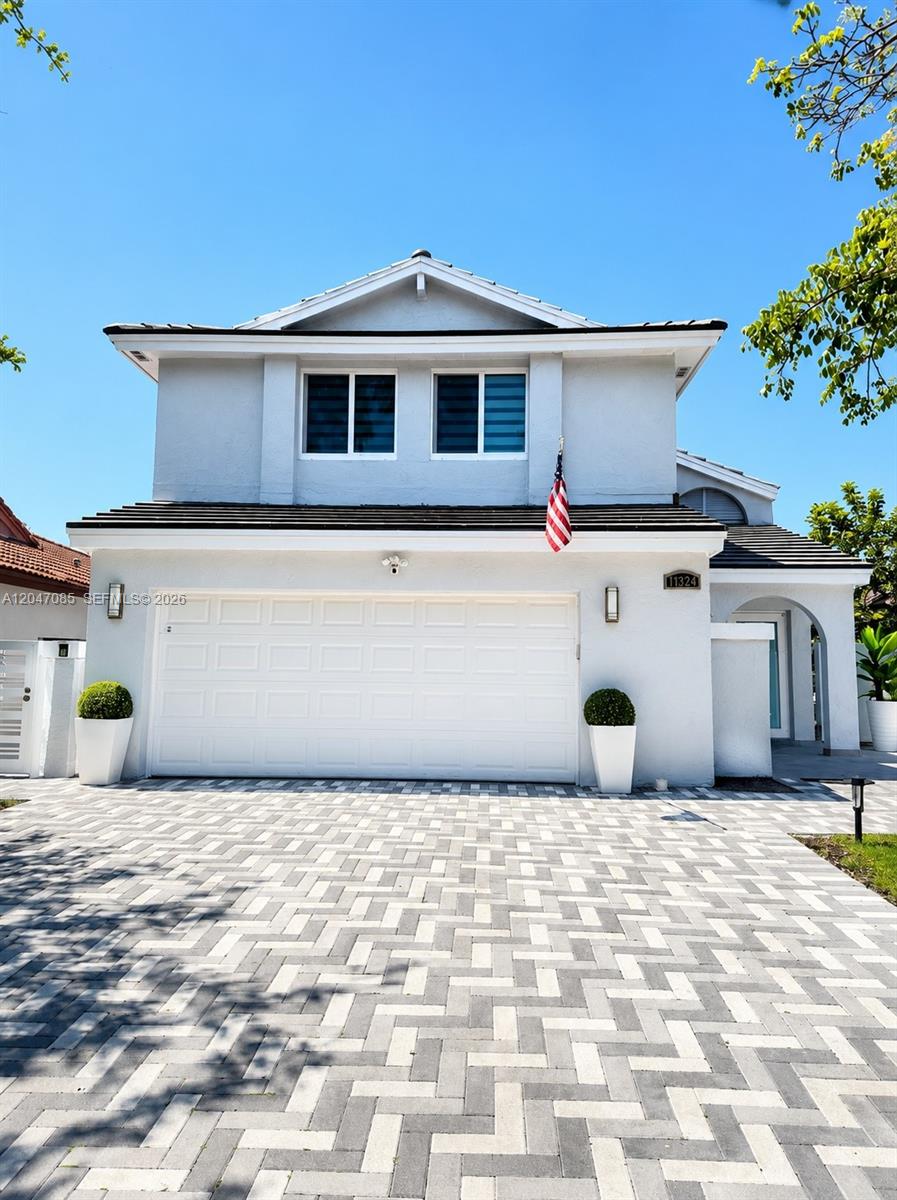 A two-story house with a white garage, paved driveway, and an American flag — 17324 NW 63rd Ave, Hialeah FL 33015, HIALEAH, FL