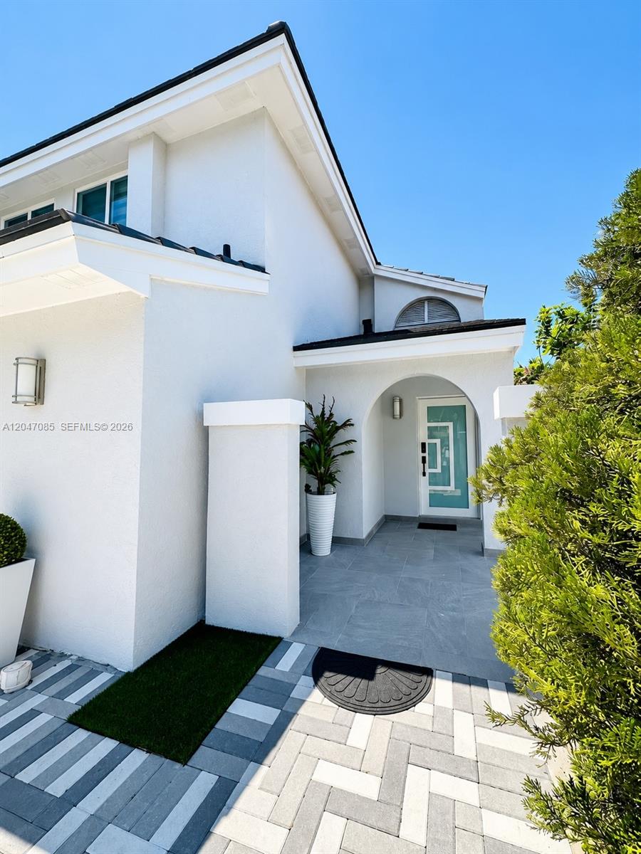 The exterior of a white house features a tiled entryway, a modern door, and landscaping — 17324 NW 63rd Ave, Hialeah FL 33015, HIALEAH, FL