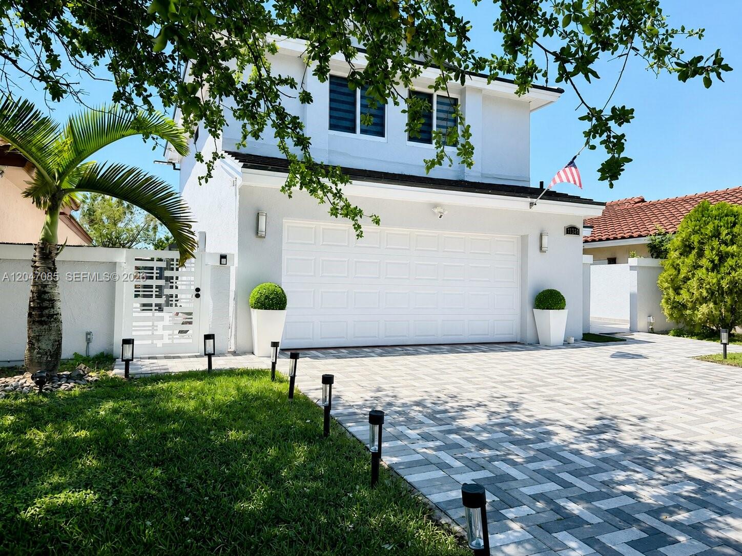 A modern kitchen features white cabinetry, a large quartz island with a cooktop, and stainless appliances — 17324 NW 63rd Ave, Hialeah FL 33015, HIALEAH, FL