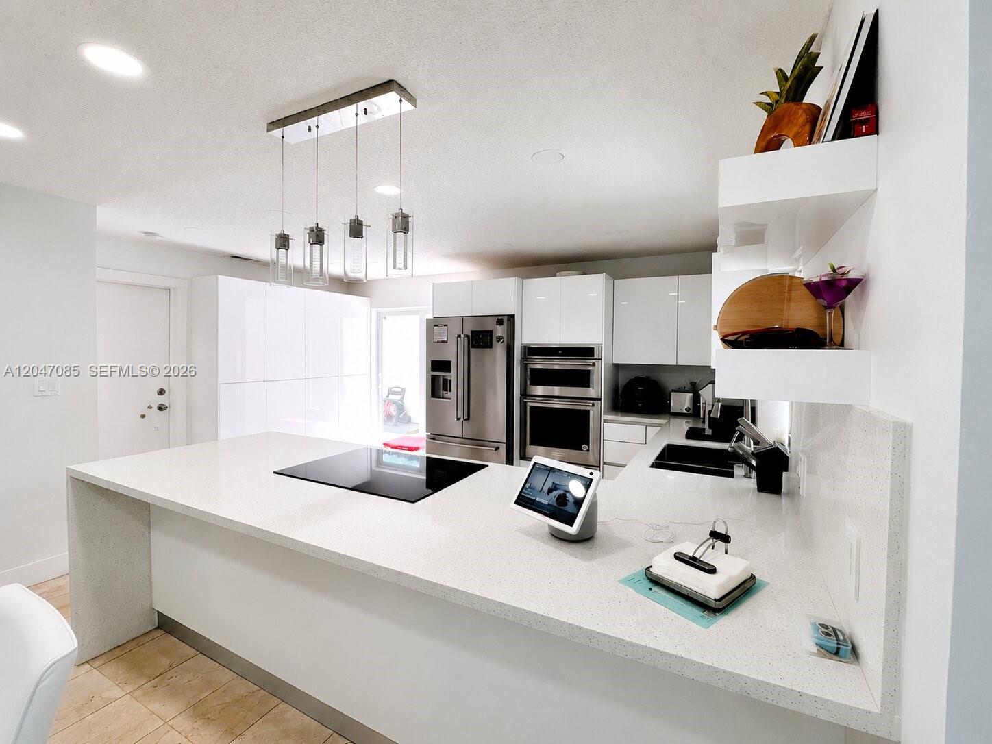 A modern kitchen features white cabinets, stainless steel appliances, and a large quartz island — 17324 NW 63rd Ave, Hialeah FL 33015, HIALEAH, FL