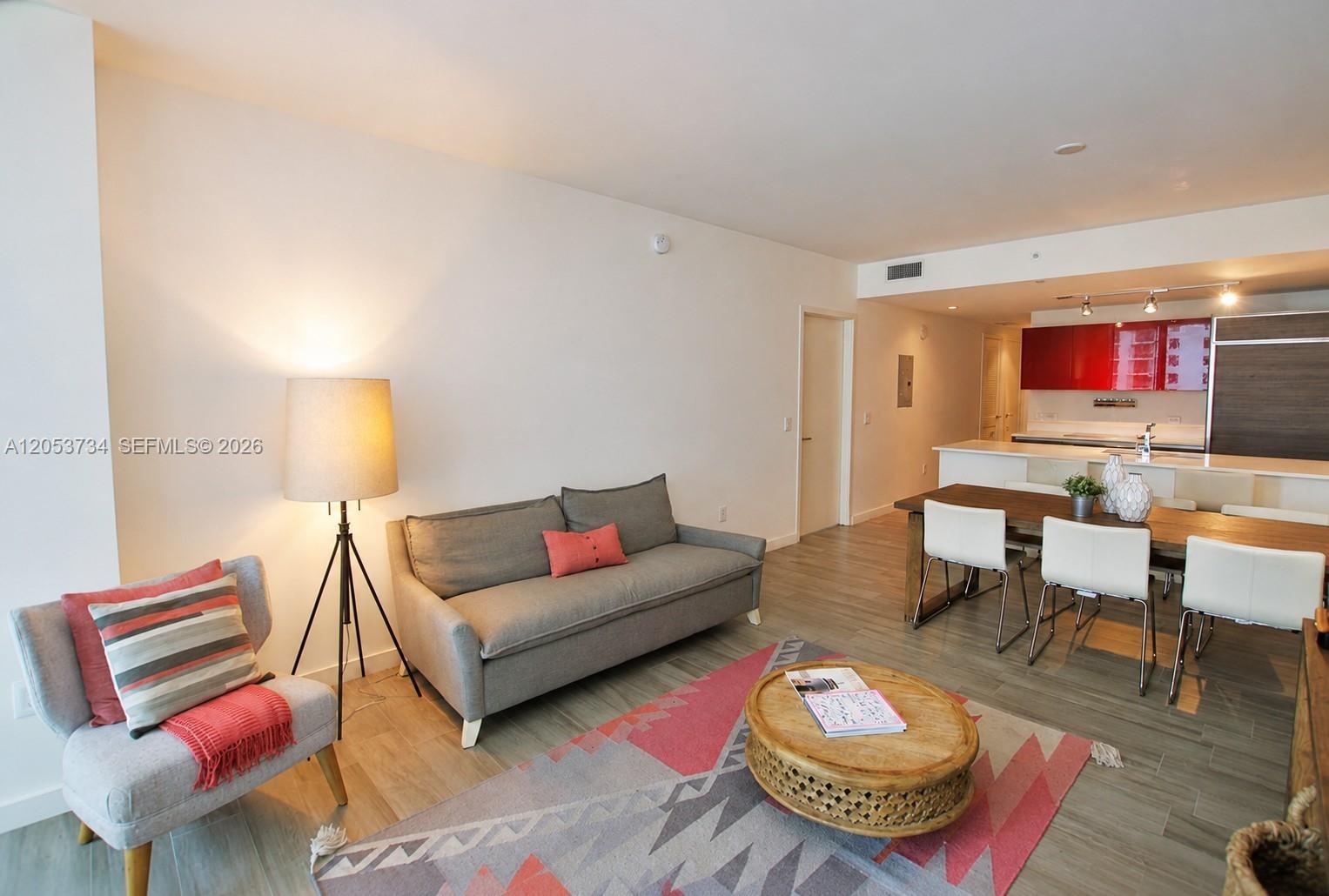 A living and dining area features a grey sofa, patterned rug, and open kitchen — 1100 S Miami Ave # 1711, Miami FL 33130, MIAMI, FL