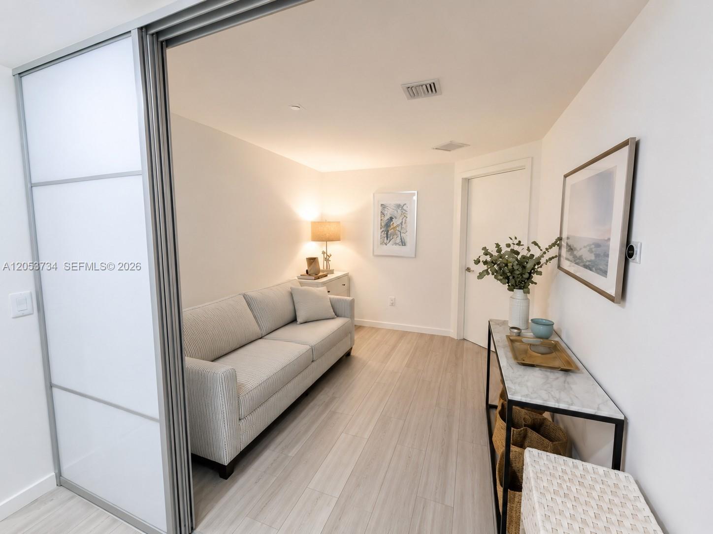 A small room features a striped sofa, light wood flooring, and a marble-topped console table — 1100 S Miami Ave # 1711, Miami FL 33130, MIAMI, FL