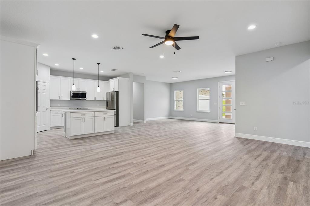 An open-concept kitchen and living area features white cabinetry, a center island, and wood-look flooring — 2043 WATERSEDGE DRIVE, DELTONA, FL
