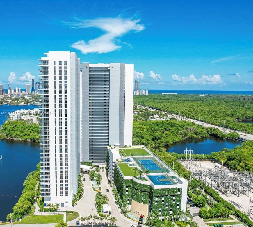 An aerial view of a tall residential building with a tennis court on its parking garage — 16385 Biscayne Blvd # 7, North Miami Beach FL 33160, NORTH MIAMI BEACH, FL