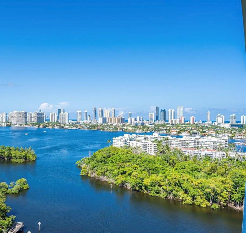 A high-angle view shows a body of water, lush green trees, and a distant city skyline — 16385 Biscayne Blvd # 7, North Miami Beach FL 33160, NORTH MIAMI BEACH, FL
