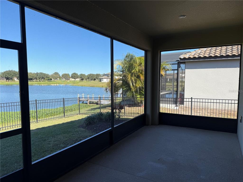 A screened-in patio overlooks a lake, a grassy lawn, and a neighboring house — 3964 CARRICK BEND DR, KISSIMMEE, FL