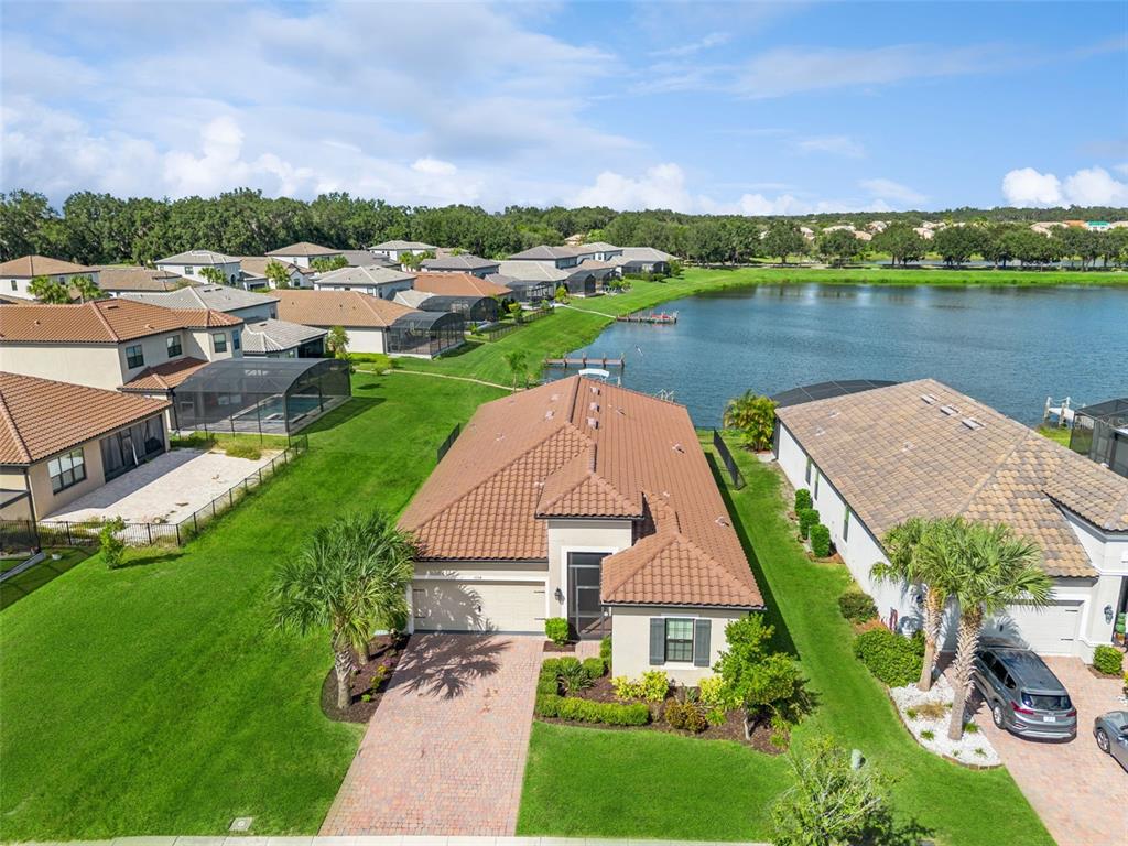 An aerial view shows a suburban house with a tile roof and a backyard lake — 3964 CARRICK BEND DR, KISSIMMEE, FL
