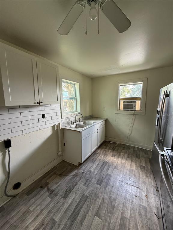 A kitchen features white cabinets, a subway tile backsplash, a stainless steel sink, and wood-look flooring — 2712 E COLUMBUS DRIVE, TAMPA, FL