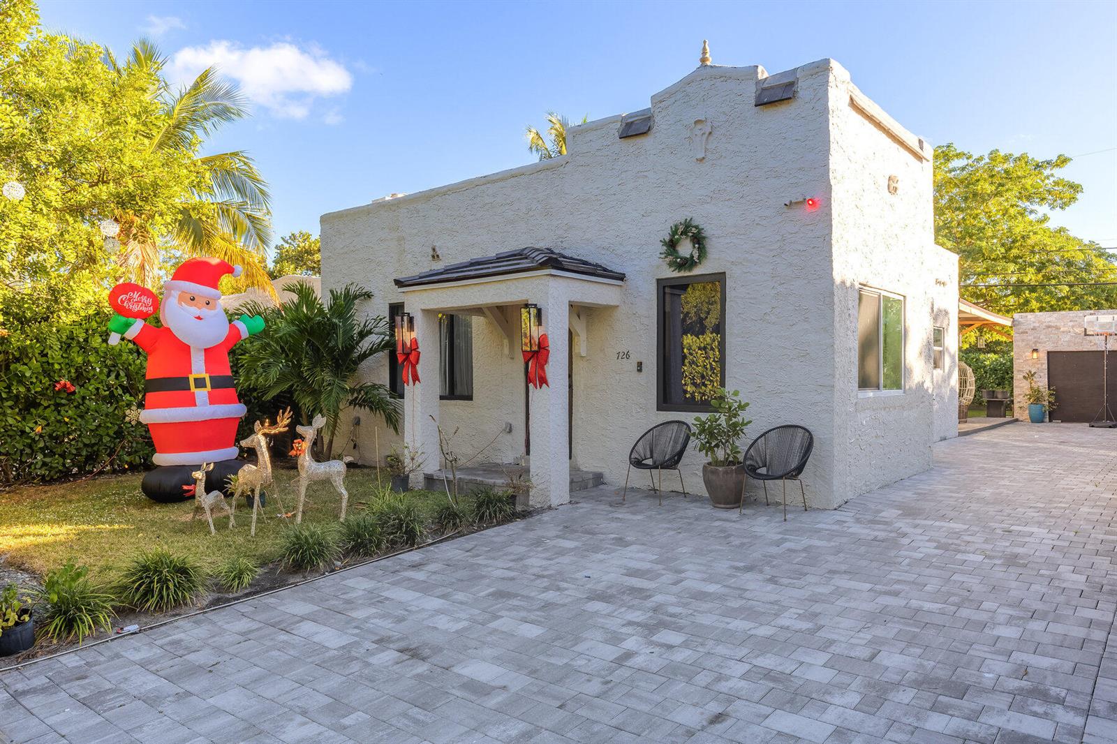 A stucco house with a paved driveway, Christmas decorations, and two chairs on the front patio — 726 Lytle Street, West Palm Beach FL 33405, WEST PALM BEACH, FL
