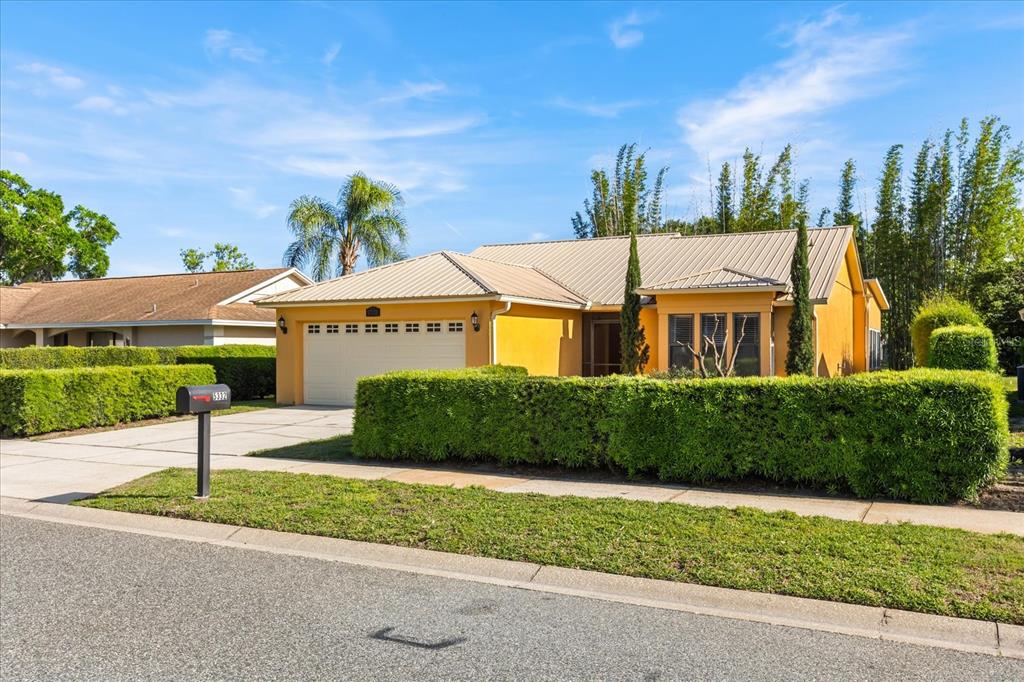 A yellow single-story house with a metal roof and a manicured hedge in the front yard — 5332 DORRINGTON LANE, ORLANDO, FL