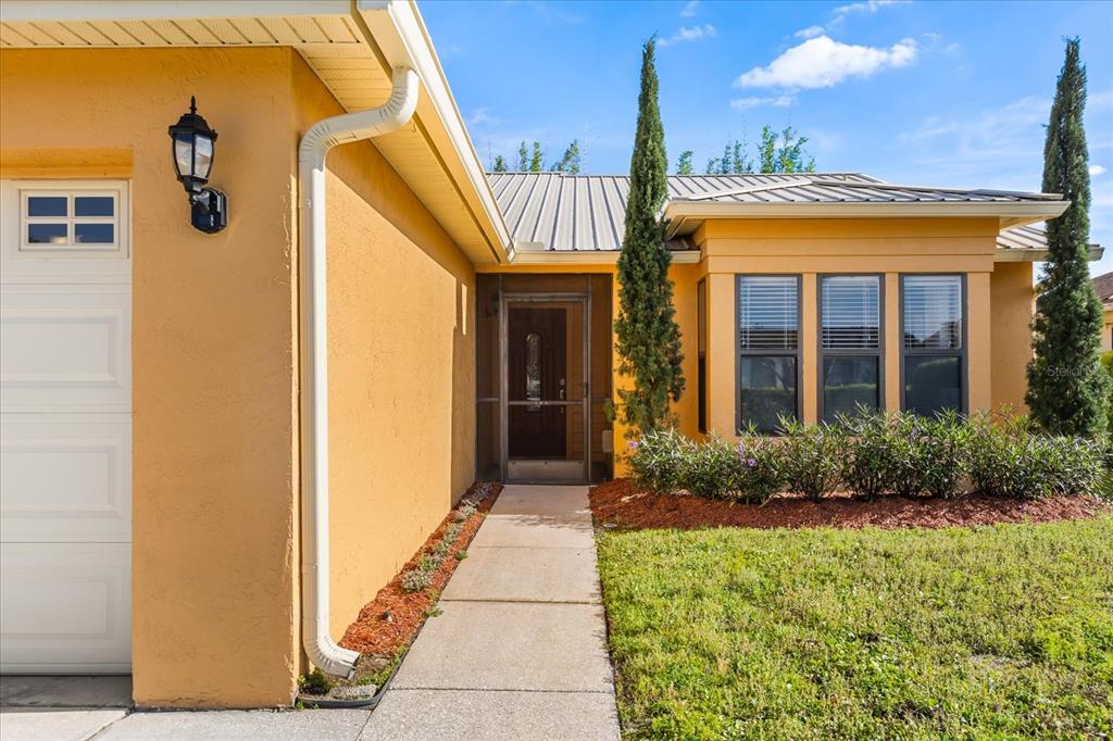 A yellow house exterior features a concrete walkway leading to a screened front door — 5332 DORRINGTON LANE, ORLANDO, FL