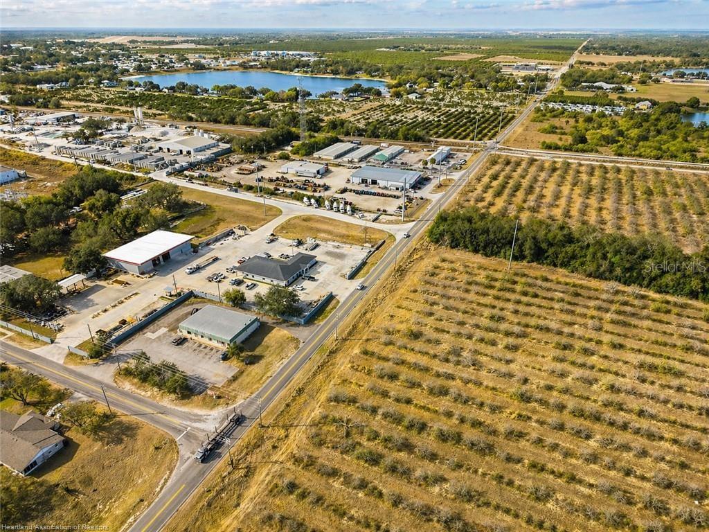 An aerial view shows commercial buildings, a road, and surrounding agricultural fields and trees — 298 COUNTY ROAD 17A W, AVON PARK, FL