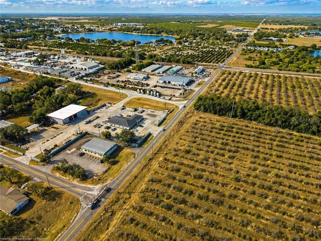 This aerial view shows a commercial property with several buildings situated next to agricultural fields — 298 COUNTY ROAD 17A W, AVON PARK, FL