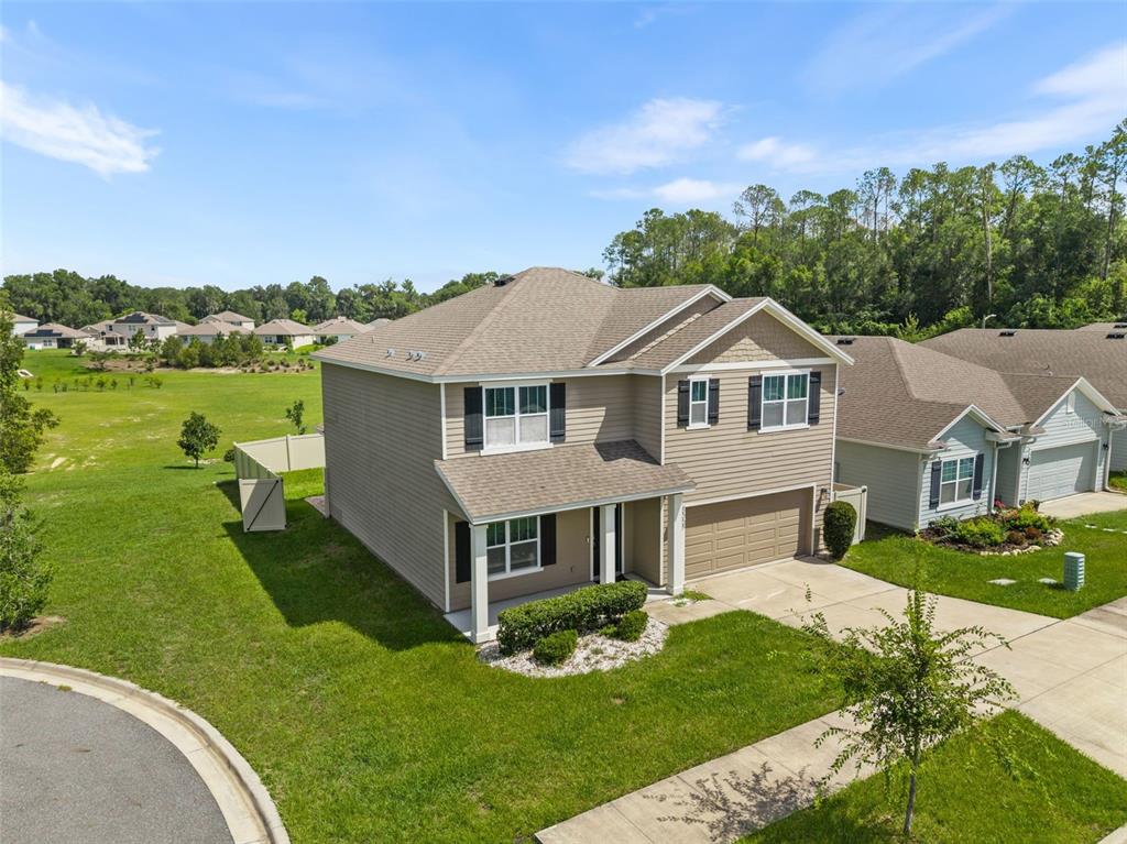 An aerial view of a two-story suburban house with tan siding and a two-car garage — 8008 SW 62ND COURT, GAINESVILLE, FL