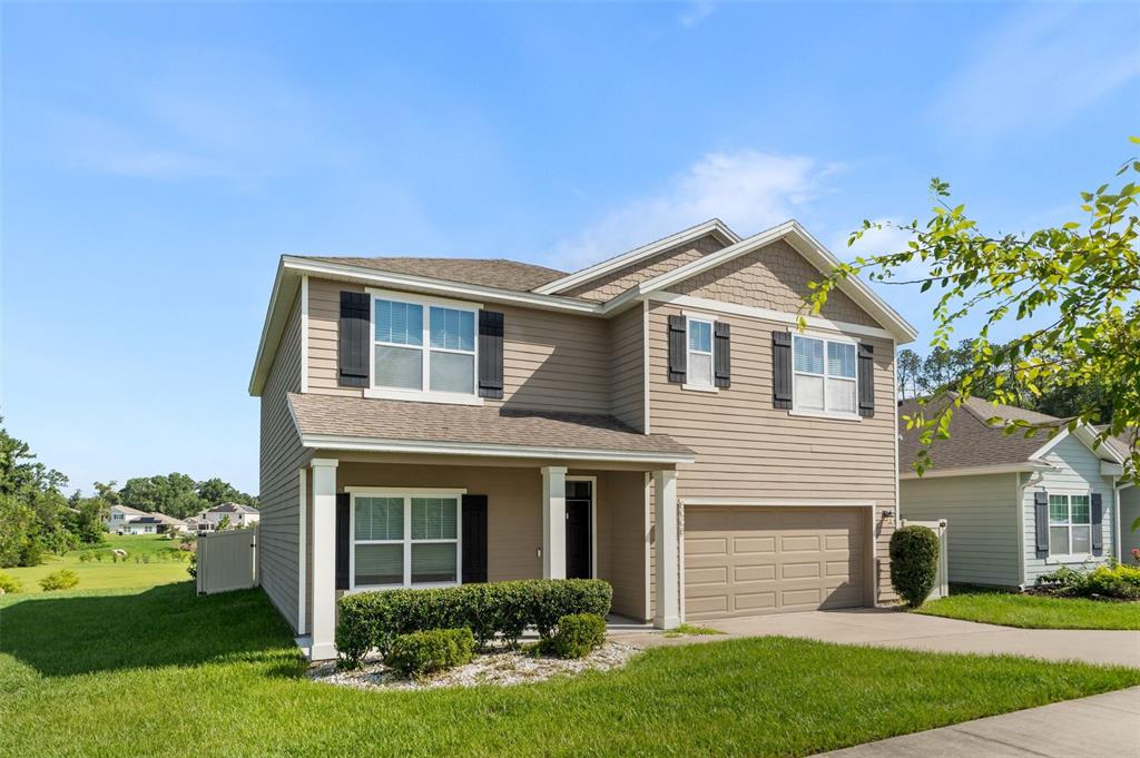 A two-story suburban house with tan siding, a front porch, and an attached garage — 8008 SW 62ND COURT, GAINESVILLE, FL