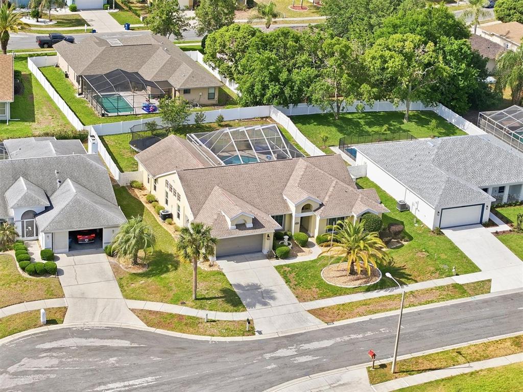 An aerial view shows a suburban house with a pool enclosure and a fenced yard — 1049 LARKIN ROAD, SPRING HILL, FL