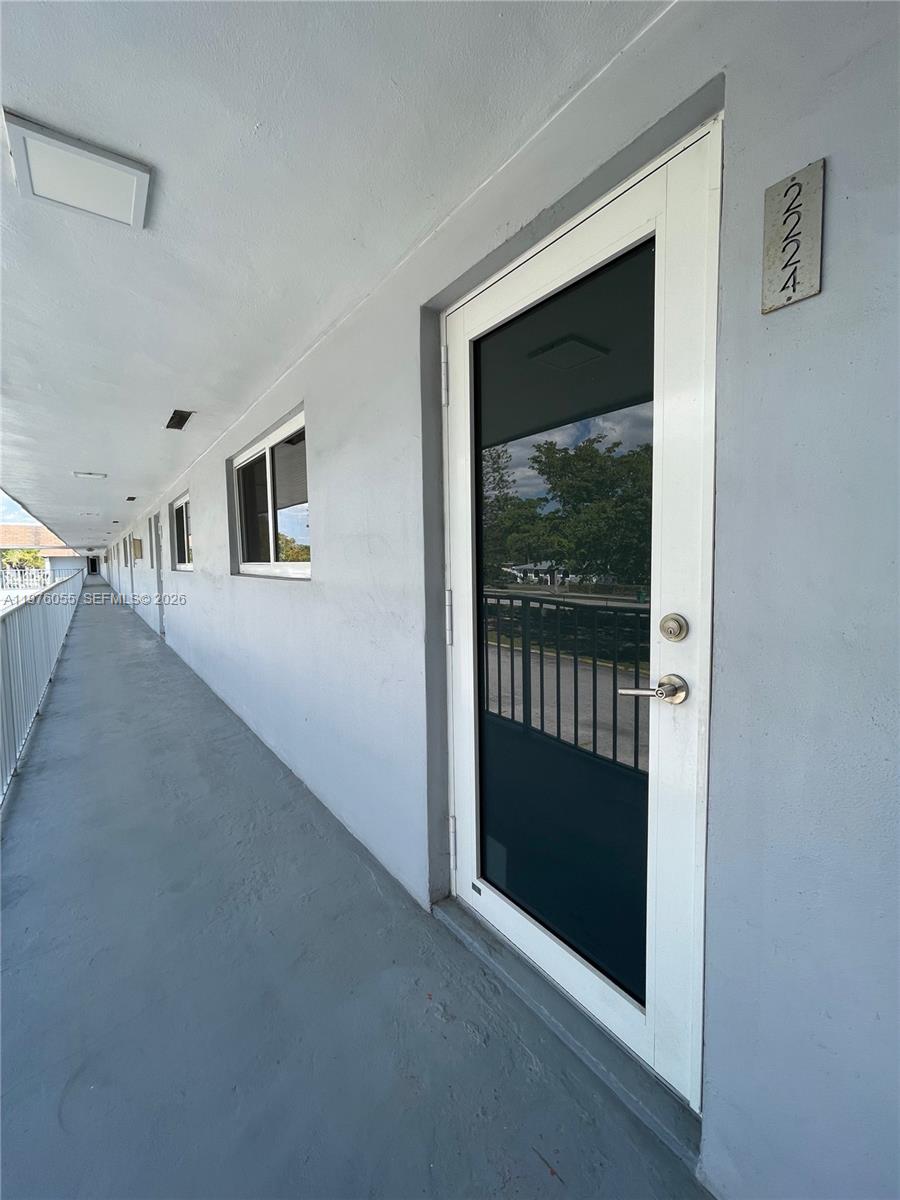 A view of an exterior apartment walkway with a white door labeled 2224 — 19255 NE 2nd Ave # 2224, Miami FL 33179, MIAMI, FL