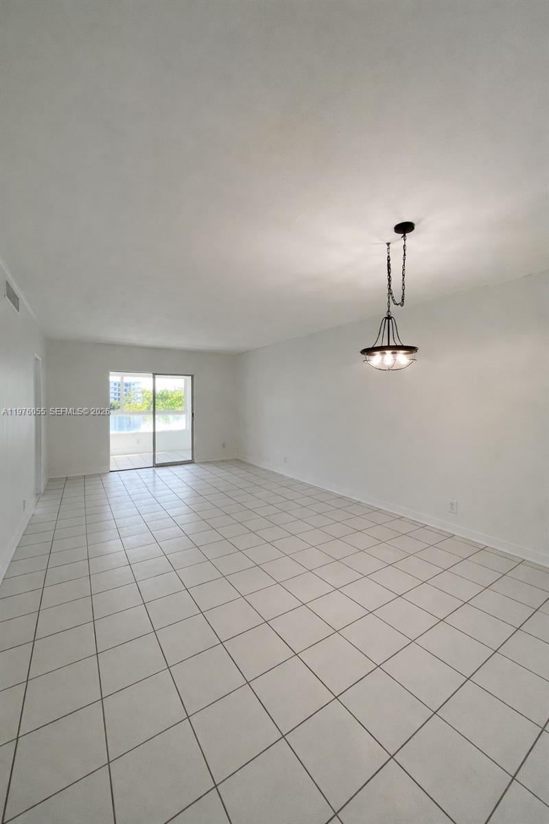 An empty room features white walls, light-colored tile flooring, and a hanging pendant light — 19255 NE 2nd Ave # 2224, Miami FL 33179, MIAMI, FL