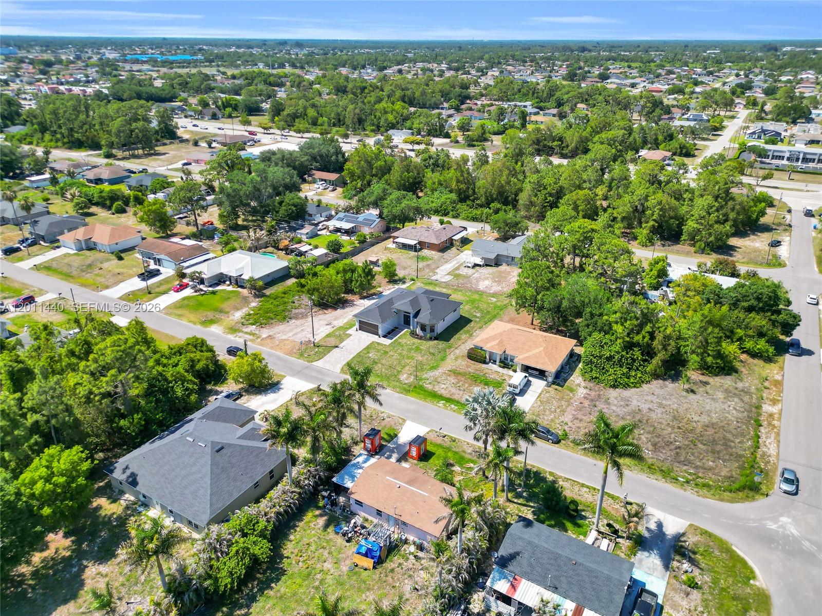 An aerial view shows several single-family homes surrounded by trees and paved streets — 4204 3RD ST W, Lehigh Acres FL 33971, LEHIGH ACRES, FL