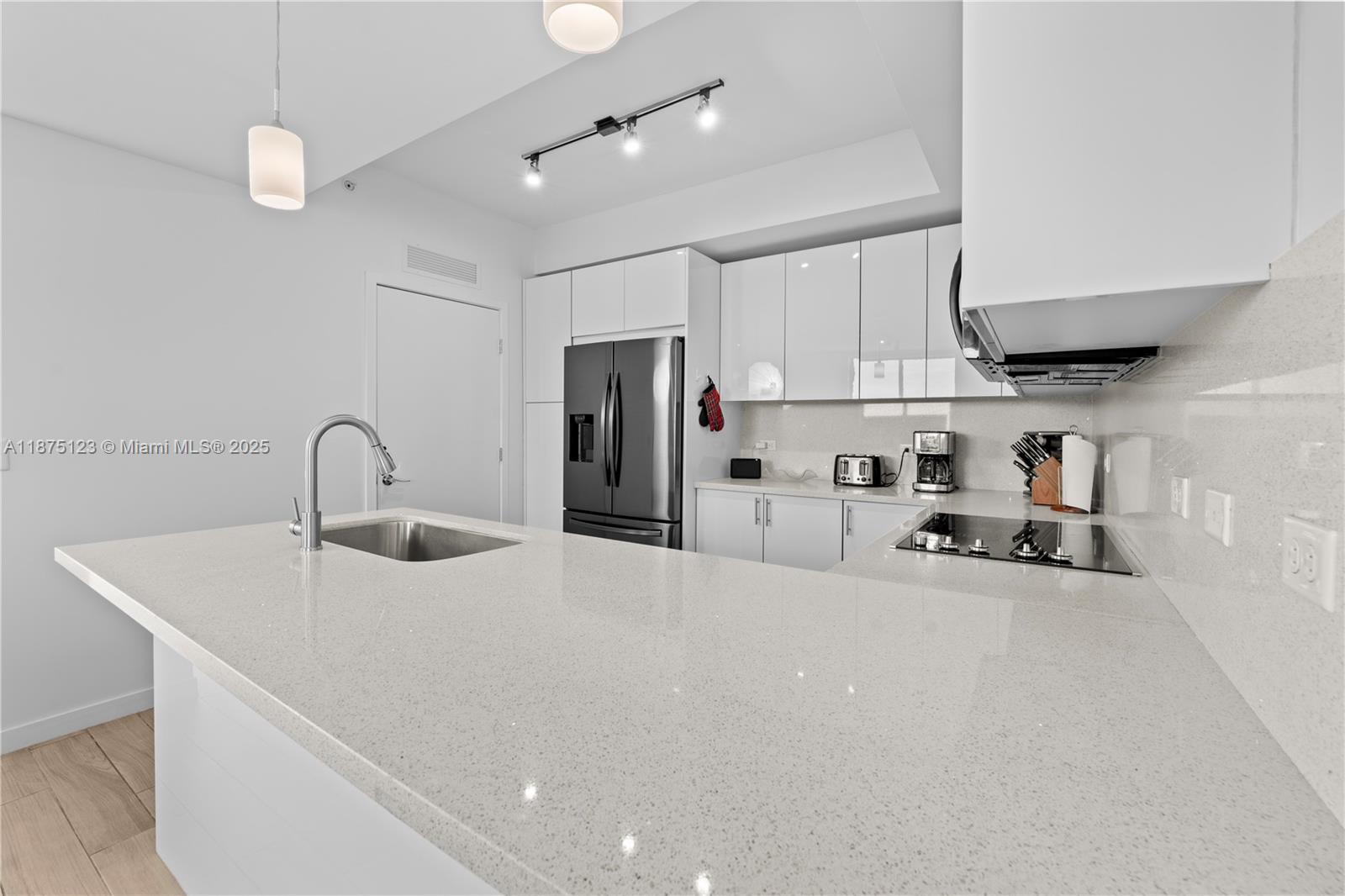 A modern kitchen features white glossy cabinets, a quartz island, and stainless steel appliances — 999 SW 1st Ave # 3304, Miami FL 33130, MIAMI, FL