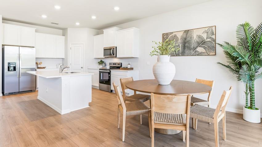 A bright kitchen and dining area features white cabinetry, stainless steel appliances, and wood flooring — 10730 RABBIT GROVE TRAIL, PARRISH, FL