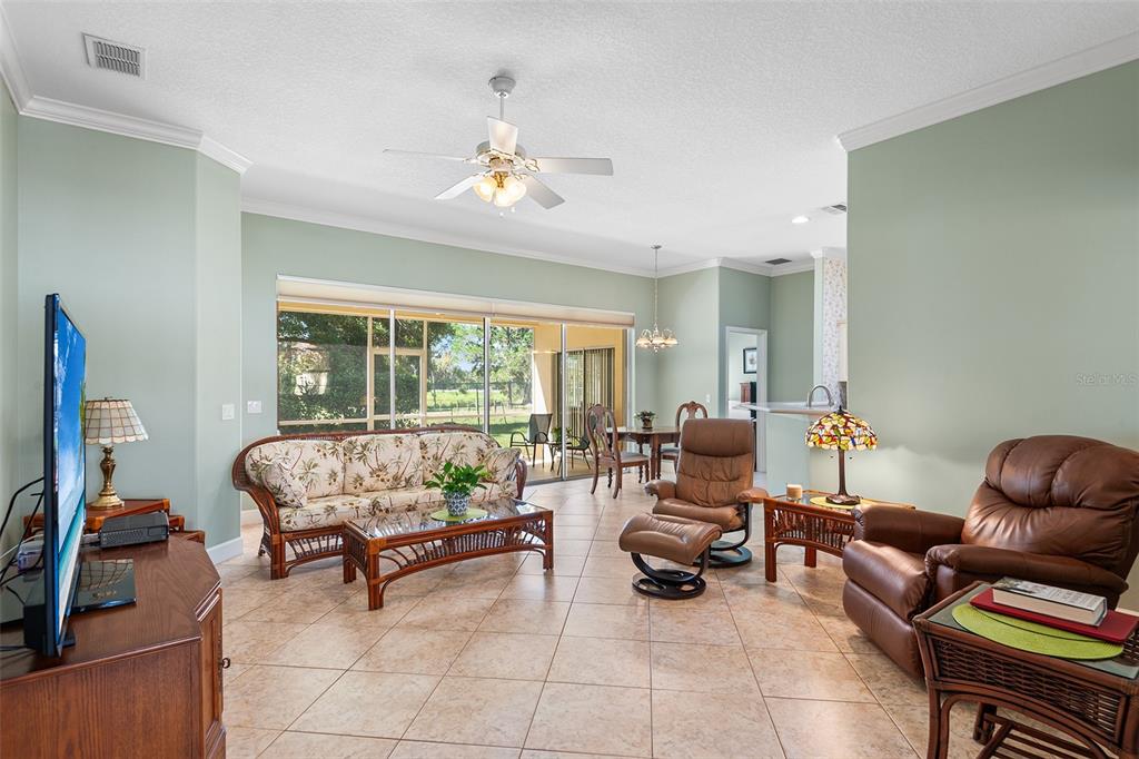 A living room with tile floors, a ceiling fan, and a sliding glass door view — 126 LAKE REGION CIRCLE, WINTER HAVEN, FL