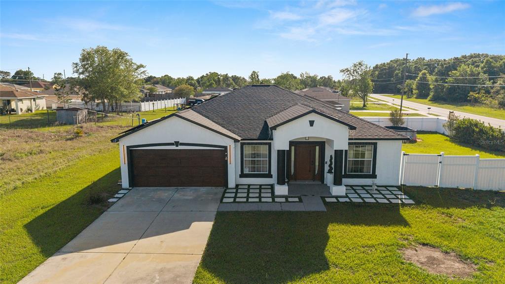 A single-story house with a white exterior, dark trim, a two-car garage, and a driveway — 2 JUNIPER TERRACE, OCALA, FL