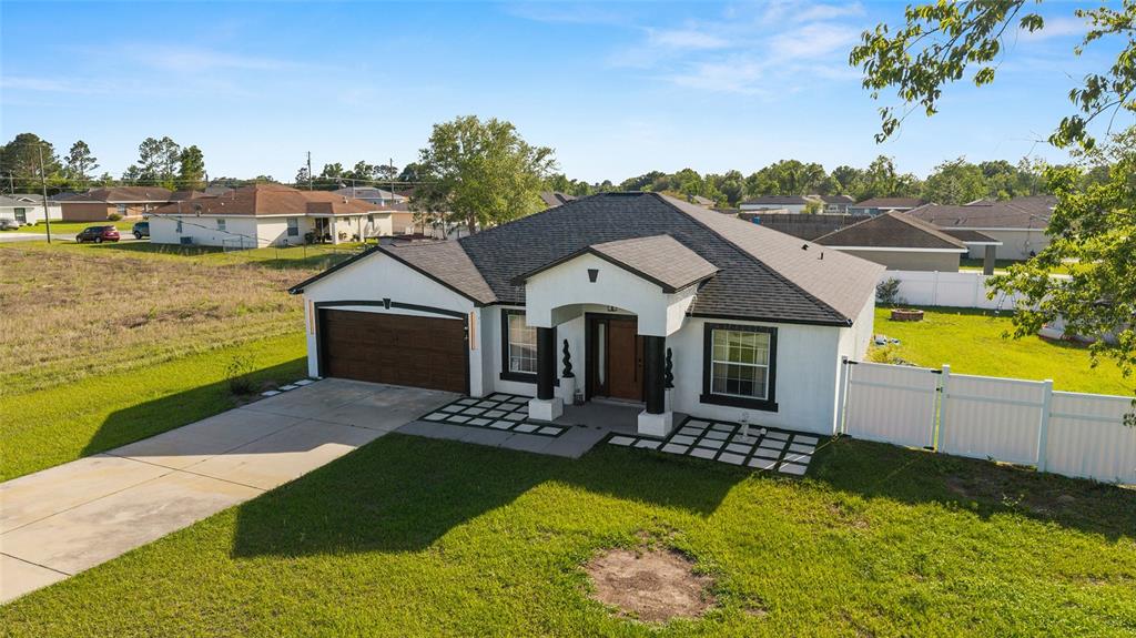 An aerial view of a single-story house with a white exterior, dark roof, and garage — 2 JUNIPER TERRACE, OCALA, FL