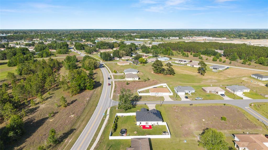 An aerial view shows a suburban neighborhood with houses, a winding road, and surrounding trees — 2 JUNIPER TERRACE, OCALA, FL