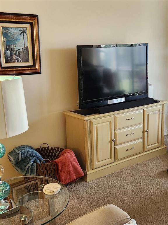 A television sits on a light-colored wooden cabinet next to a basket of towels — 6505 STONE RIVER ROAD UNIT 203, BRADENTON, FL