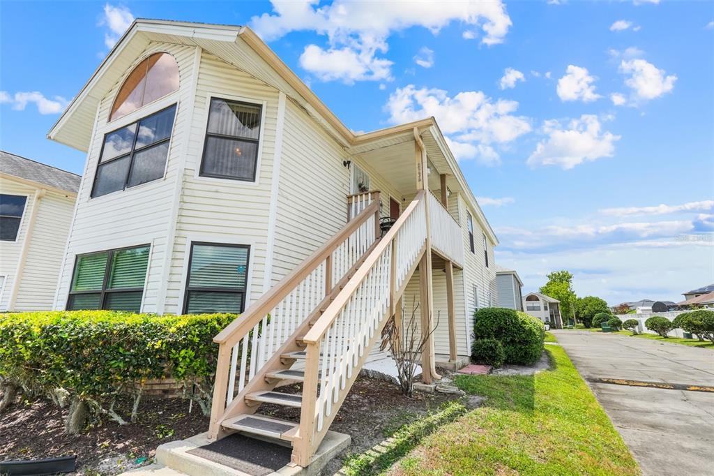 Exterior view of a two-story residential building with light siding and an outdoor staircase — 2734 RIO GRANDE TRAIL UNIT 2734, KISSIMMEE, FL