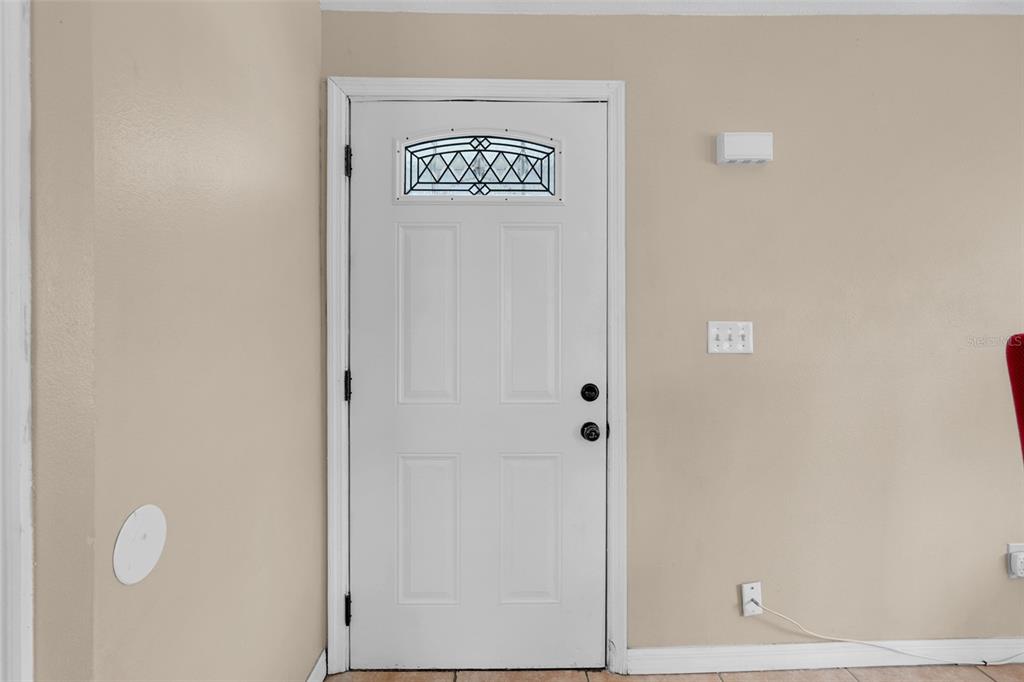A white front door with a decorative glass insert is set in a beige wall — 2734 RIO GRANDE TRAIL UNIT 2734, KISSIMMEE, FL