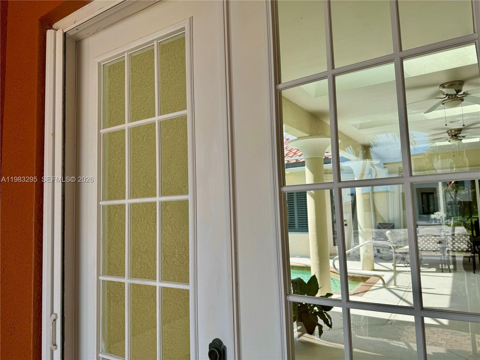 A close-up view of white French doors looking out onto a patio with a pool — 1740 Ludlow Rd # 1740, Marco Island FL 34145, MARCO ISLAND, FL