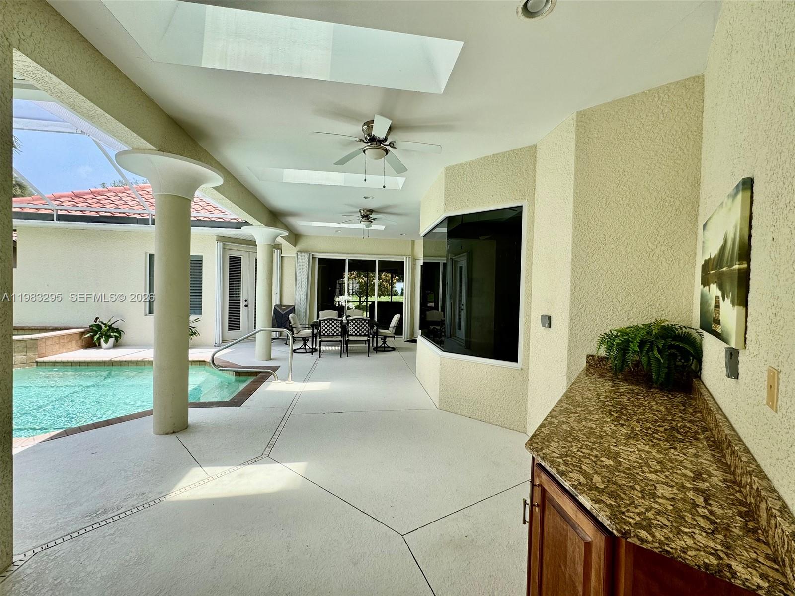 A covered patio features a swimming pool, granite-topped outdoor kitchen, and ceiling fans — 1740 Ludlow Rd # 1740, Marco Island FL 34145, MARCO ISLAND, FL