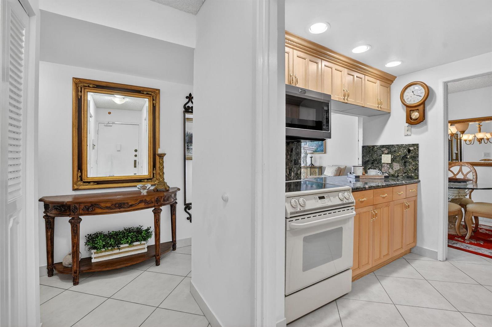 A view from a tiled hallway into a kitchen with light wood cabinets and appliances — 2121 N Ocean Boulevard # 805w, Boca Raton FL 33431, BOCA RATON, FL