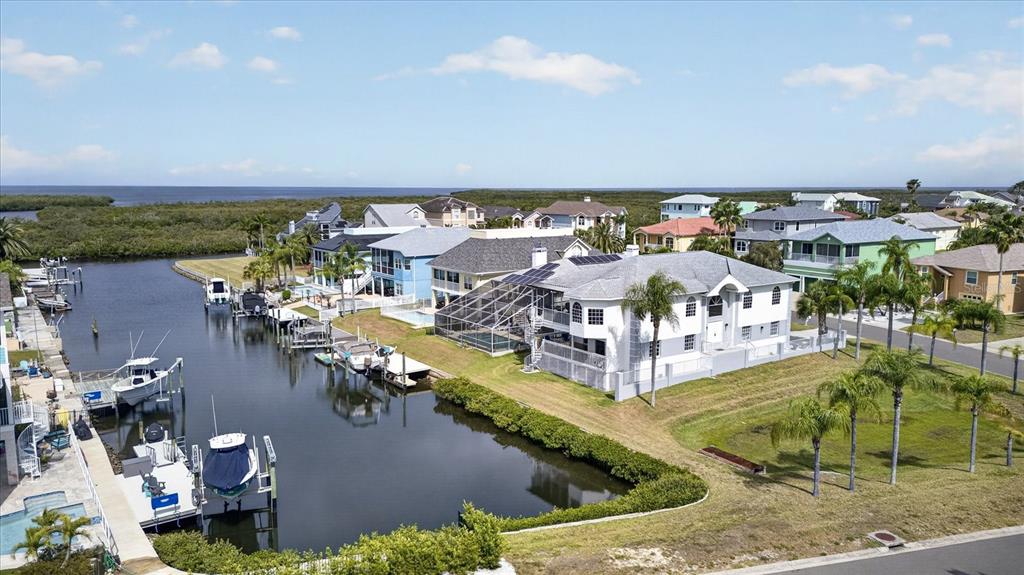 An aerial view shows waterfront houses with boat docks along a canal near the coast — 4340 SEAGULL DRIVE, NEW PORT RICHEY, FL