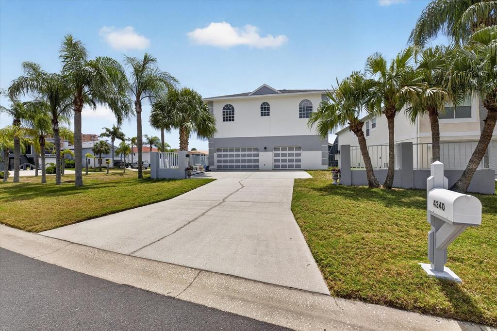 A two-story house with a concrete driveway, two garage doors, and several palm trees — 4340 SEAGULL DRIVE, NEW PORT RICHEY, FL