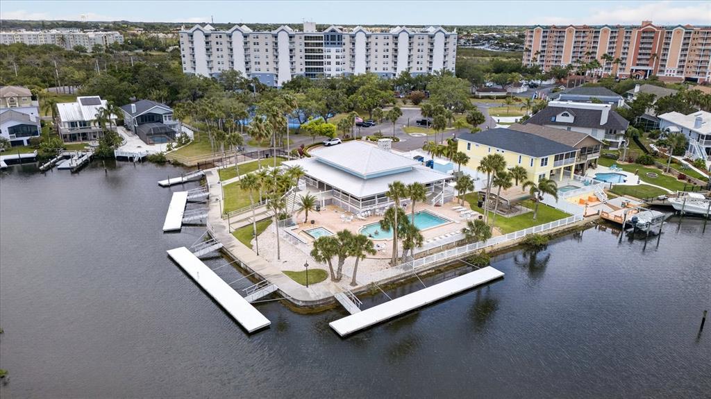 An aerial view shows a waterfront clubhouse with a pool, docks, and surrounding residential buildings — 4340 SEAGULL DRIVE, NEW PORT RICHEY, FL