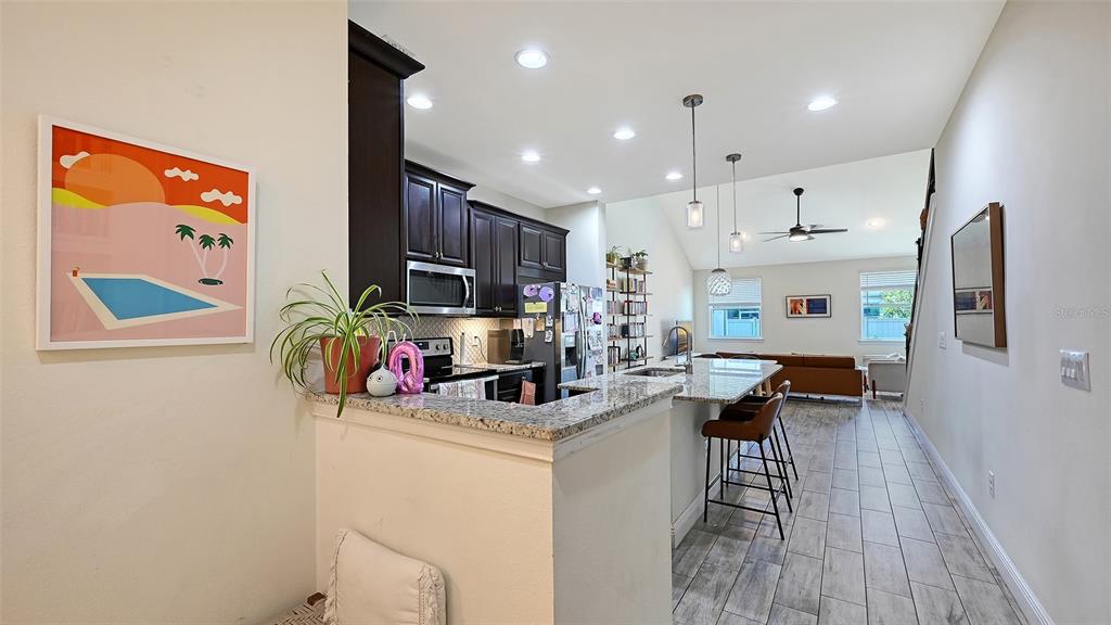 A kitchen with dark cabinets and granite countertops overlooks a living area with tile floors — 3693 DIVOT LANE, SARASOTA, FL