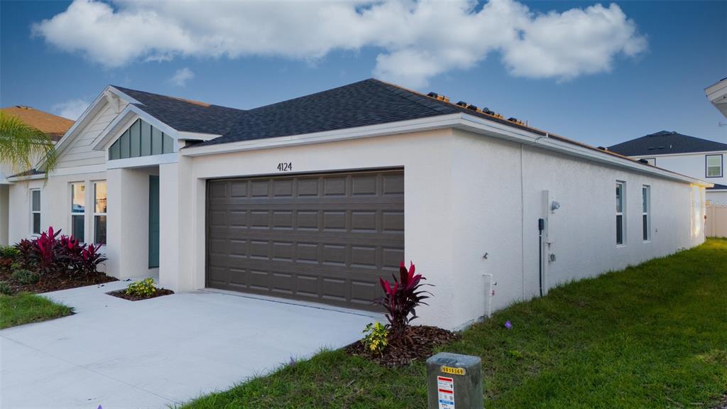 A single-story house with a white stucco exterior, a brown garage door, and a shingled roof — 4124 RIVER BEACON BOULEVARD, DAVENPORT, FL