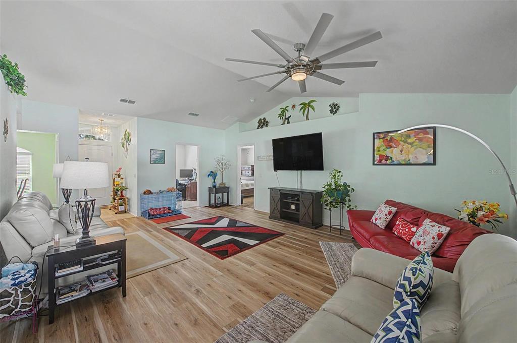 A living room with light green walls, wood-look flooring, a vaulted ceiling, and two sofas — 1621 DOVES VIEW CIRCLE, AUBURNDALE, FL