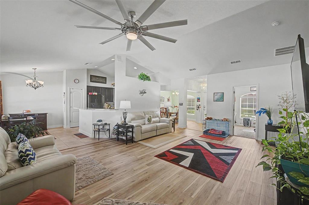 A living room with light wood-look flooring, a large ceiling fan, and a white sofa — 1621 DOVES VIEW CIRCLE, AUBURNDALE, FL