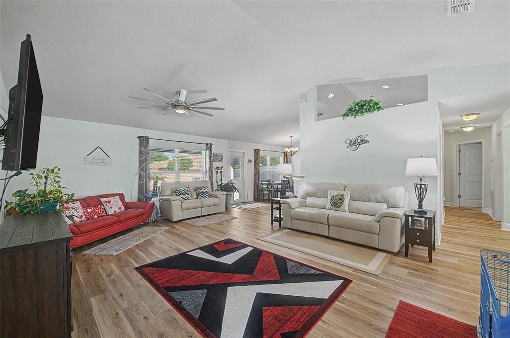 A living room features light wood flooring, a red sofa, two beige sofas, and a rug — 1621 DOVES VIEW CIRCLE, AUBURNDALE, FL