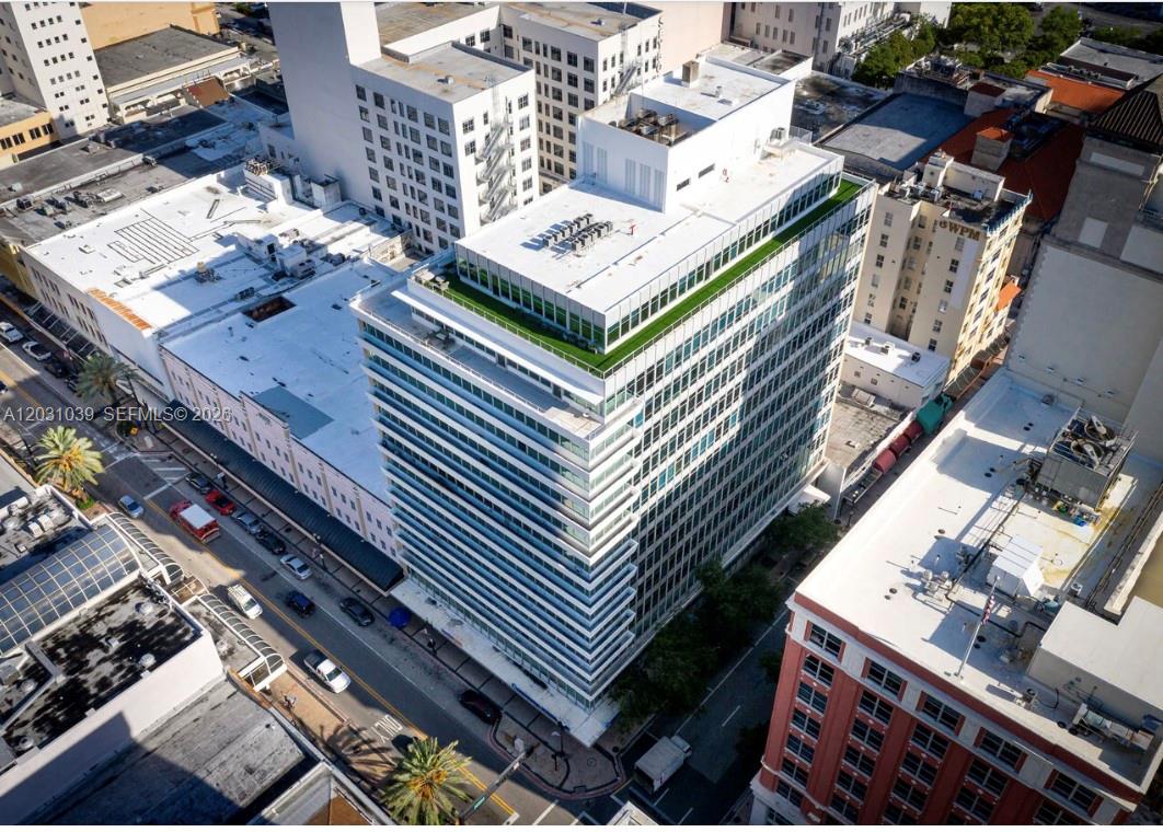 An aerial view shows a modern glass-facade office building surrounded by older urban structures — 14 NE 1st Ave, Miami FL 33132, MIAMI, FL