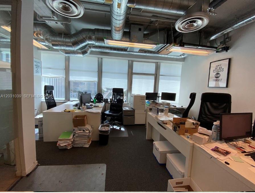 An office space features two desks, ergonomic chairs, exposed ceiling ductwork, and large windows — 14 NE 1st Ave, Miami FL 33132, MIAMI, FL