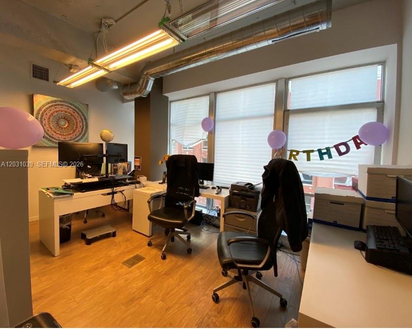 This office space features two desks, black rolling chairs, large windows, and purple birthday balloons — 14 NE 1st Ave, Miami FL 33132, MIAMI, FL