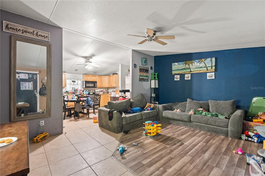 A living room with wood-look flooring and a blue accent wall opens to a kitchen — 14758 CONGRESS STREET, ORLANDO, FL