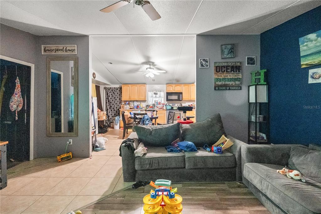 A living room with gray sofas opens into a kitchen with light wood cabinets — 14758 CONGRESS STREET, ORLANDO, FL