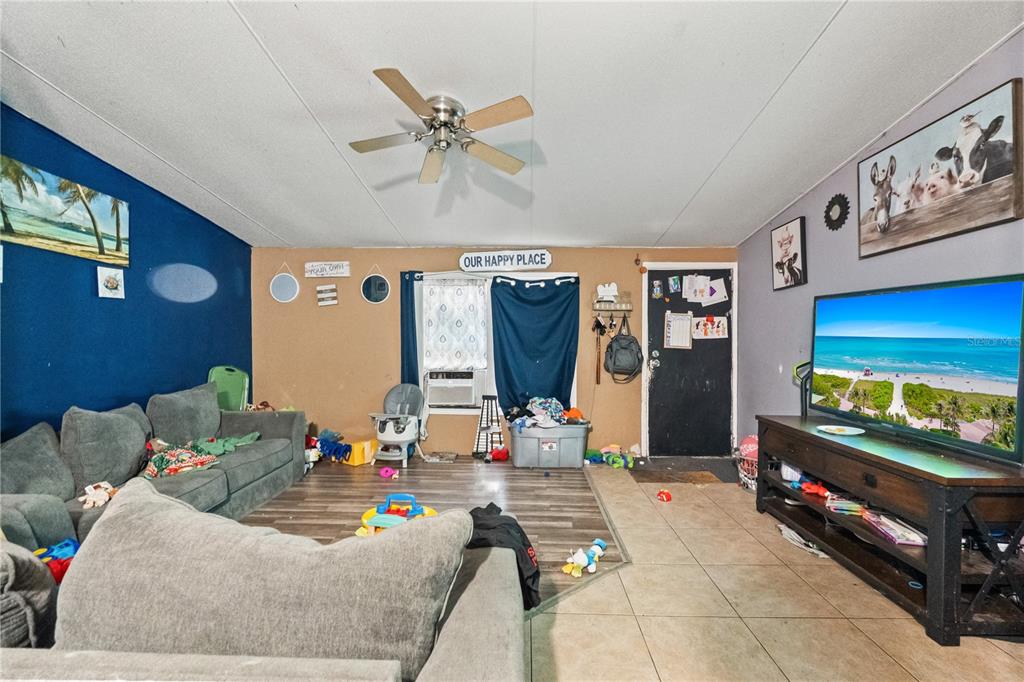 A living room features a grey sectional sofa, a television on a console, and tiled flooring — 14758 CONGRESS STREET, ORLANDO, FL
