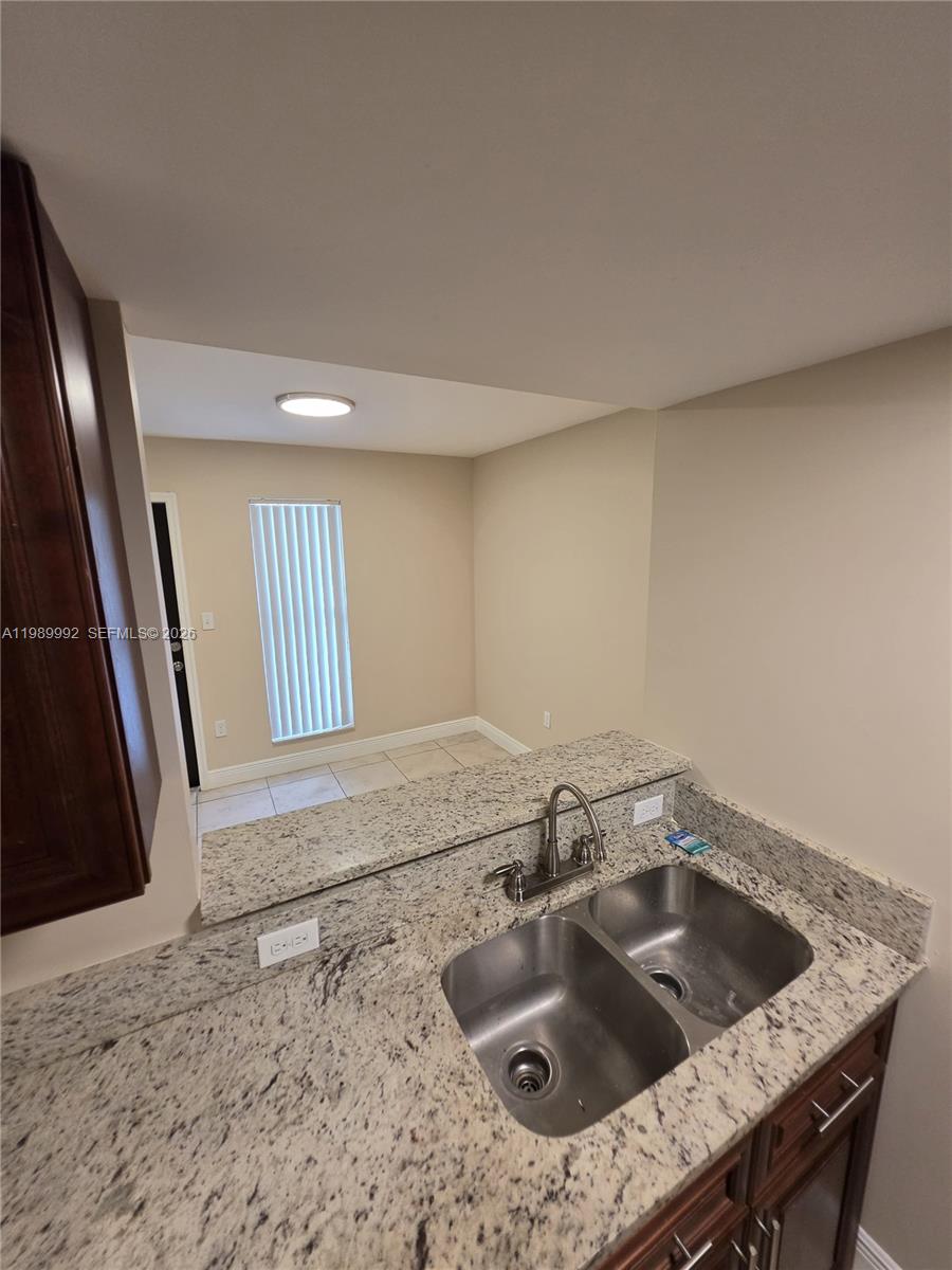 A kitchen sink with granite countertops overlooks a dining area with tile flooring — 1990 NW 4th Ct # 7, Miami FL 33136, MIAMI, FL